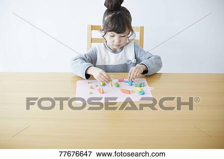 Stock Photo - Cute Japanese kid playing with clay. Fotosearch