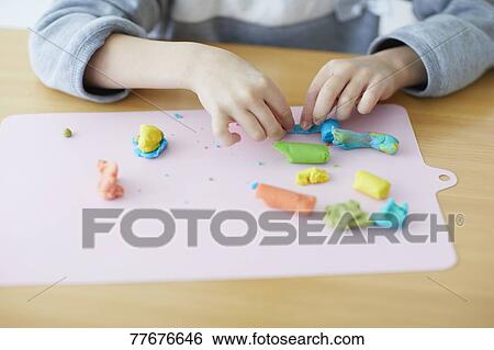 Stock Photograph - Cute Japanese kid playing with clay. Fotosearch
