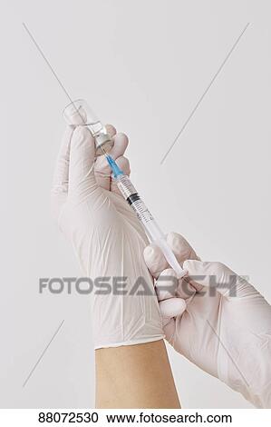 Stock Image - Doctor preparing injection. Fotosearch