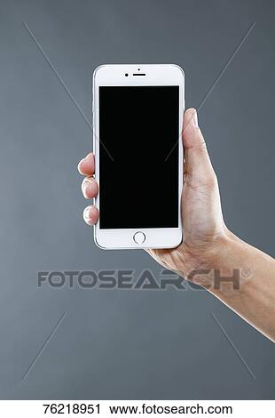 Stock Image - Hand holding smartphone. Fotosearch