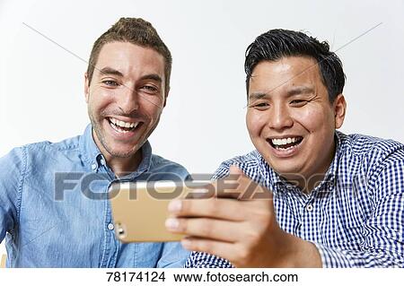 Picture - International friends enjoying content on a smartphone. Fotosearch