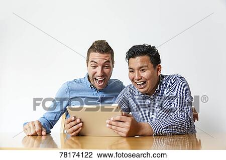 International friends enjoying content on a tablet View Large Photo Image Stock Image - International friends enjoying content on a tablet. Fotosearch
