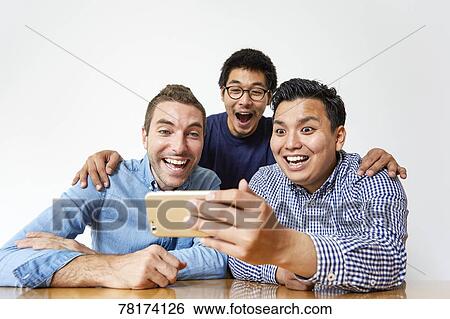 Stock Photograph - International friends enjoying content on a tablet. Fotosearch