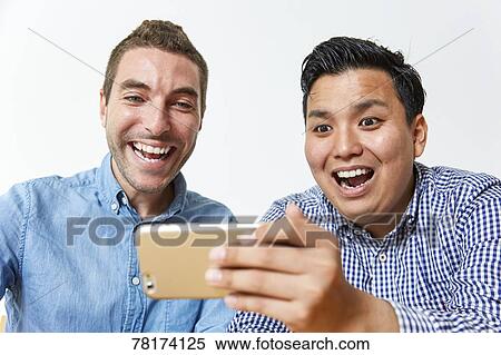 Stock Photography - International friends enjoying content on a smartphone. Fotosearch