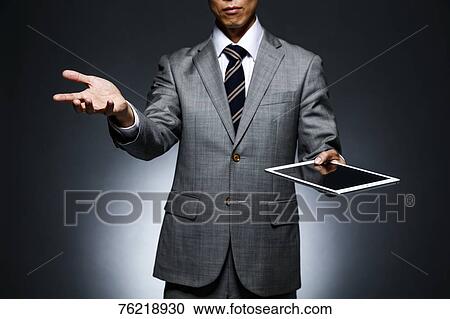 Stock Image - Japanese businessman against grey background. Fotosearch
