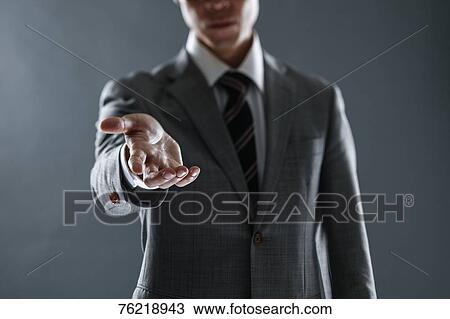 Stock Image - Japanese businessman against grey background. Fotosearch