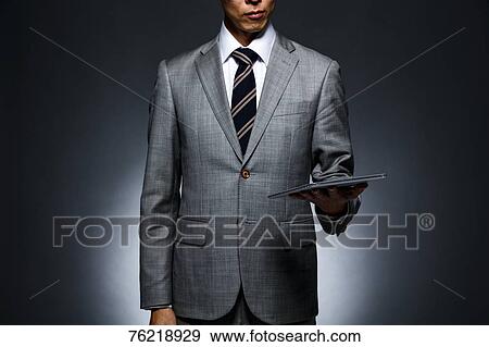 Stock Photo - Japanese businessman against grey background. Fotosearch
