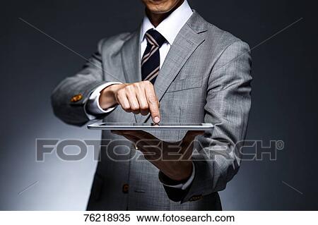 Stock Photography - Japanese businessman against grey background. Fotosearch