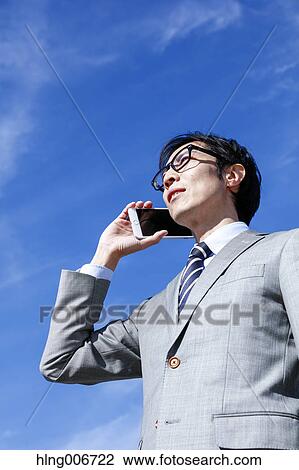 Stock Image - Japanese businessman on the phone downtown Tokyo, Japan. Fotosearch
