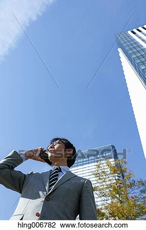 Stock Image - Japanese businessman on the phone downtown Tokyo, Japan. Fotosearch