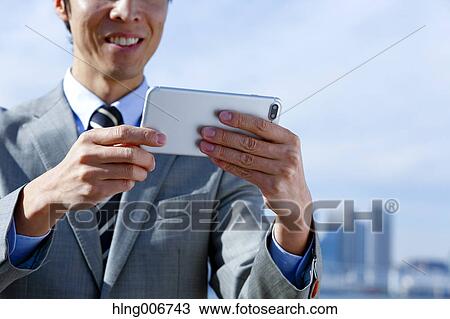 Japanese businessman with smartphone downtown Tokyo, Japan View Large Photo Image Stock Image - Japanese businessman with smartphone downtown Tokyo, Japan. Fotosearch