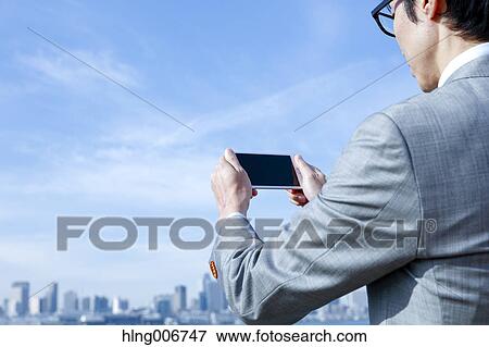 Japanese businessman with smartphone downtown Tokyo, Japan View Large Photo Image Stock Photo - Japanese businessman with smartphone downtown Tokyo, Japan. Fotosearch