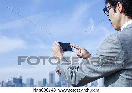 Japanese businessman with smartphone downtown Tokyo, Japan View Large Photo Image Stock Photo - Japanese businessman with smartphone downtown Tokyo, Japan. Fotosearch