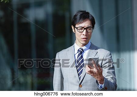 Japanese businessman with smartphone downtown Tokyo, Japan View Large Photo Image Stock Photograph - Japanese businessman with smartphone downtown Tokyo, Japan. Fotosearch