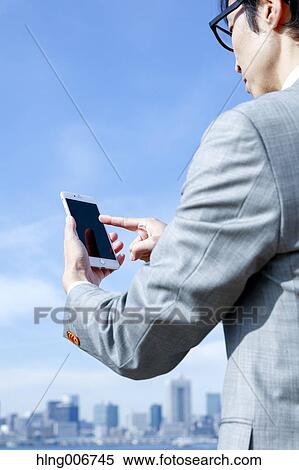 Japanese businessman with smartphone downtown Tokyo, Japan View Large Photo Image Stock Photography - Japanese businessman with smartphone downtown Tokyo, Japan. Fotosearch