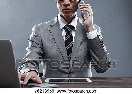 Stock Photo - Japanese businessman working at desk. Fotosearch