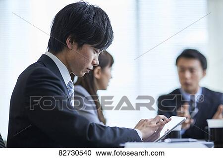Stock Image - Japanese businesspeople in a meeting. Fotosearch