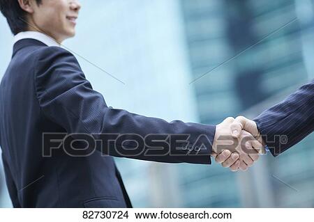 Japanese businesspeople shaking hands downtown Tokyo View Large Photo Image Picture - Japanese businesspeople shaking hands downtown Tokyo. Fotosearch
