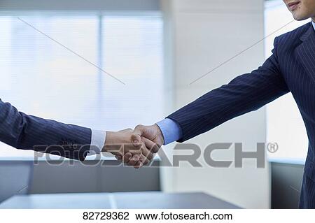 Stock Image - Japanese businesspeople shaking hands. Fotosearch