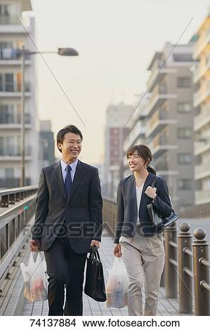 Picture - Japanese couple commuting home from work. Fotosearch