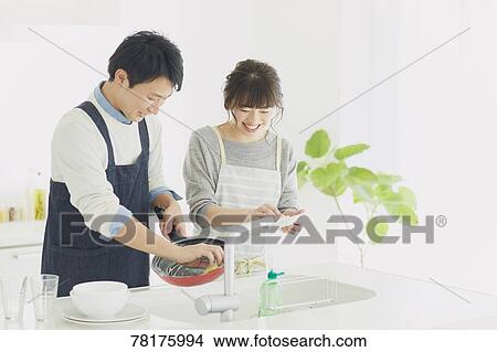 Picture - Japanese couple cooking in the kitchen. Fotosearch