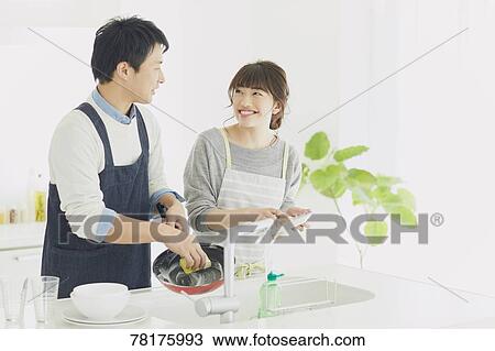 Stock Image - Japanese couple cooking in the kitchen. Fotosearch