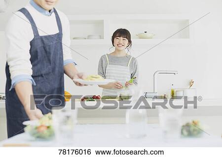 Stock Photograph - Japanese couple cooking in the kitchen. Fotosearch
