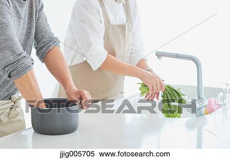 Stock Photography - Japanese couple cooking together in the kitchen. Fotosearch