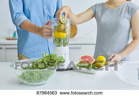 Stock Image - Japanese couple making smoothie in the kitchen. Fotosearch