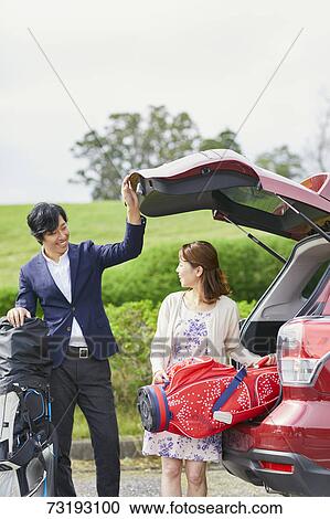 Stock Image - Japanese couple preparing to play golf. Fotosearch