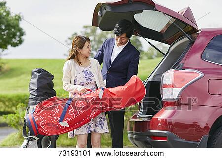 Stock Image - Japanese couple preparing to play golf. Fotosearch