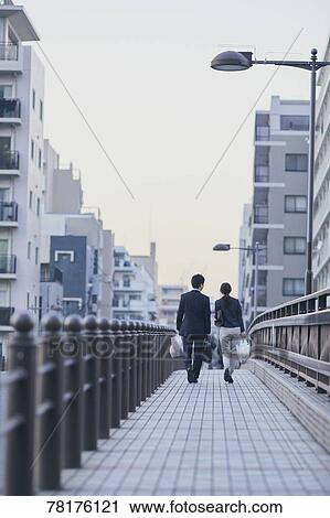 Stock Image - Japanese couple walking home from work. Fotosearch