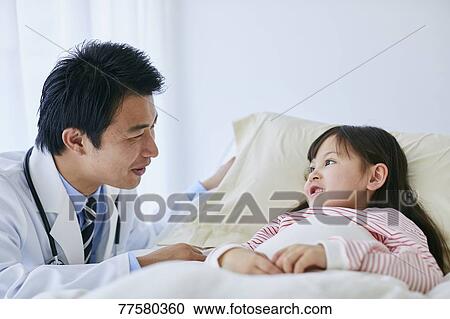 Stock Image - Japanese doctor with a patient in bed. Fotosearch