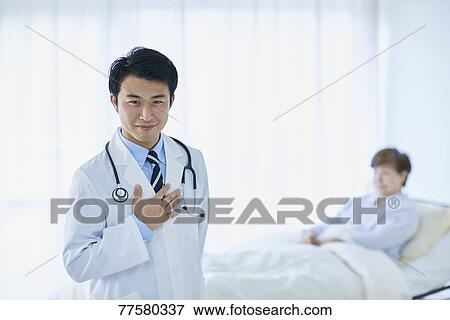 Stock Photo - Japanese doctor with a patient in bed. Fotosearch