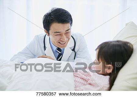 Stock Photo - Japanese doctor with a patient in bed. Fotosearch