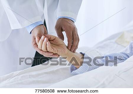 Stock Photo - Japanese doctor with a patient in bed. Fotosearch