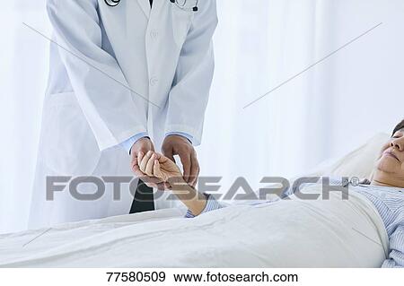 Stock Photo - Japanese doctor with a patient in bed. Fotosearch