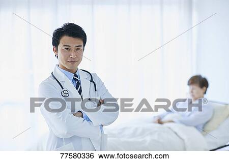 Stock Photograph - Japanese doctor with a patient in bed. Fotosearch