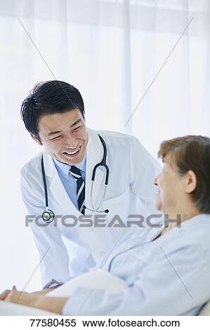 Stock Photography - Japanese doctor with a patient in bed. Fotosearch