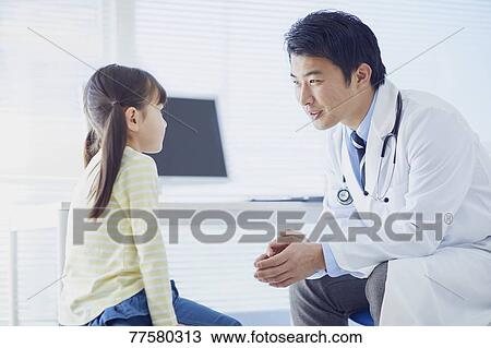 Stock Image - Japanese doctor with a patient in his studio. Fotosearch