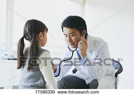 Stock Image - Japanese doctor with a patient in his studio. Fotosearch