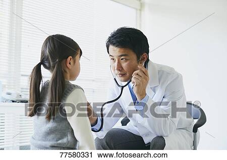 Stock Image - Japanese doctor with a patient in his studio. Fotosearch