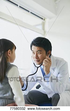 Stock Image - Japanese doctor with a patient in his studio. Fotosearch