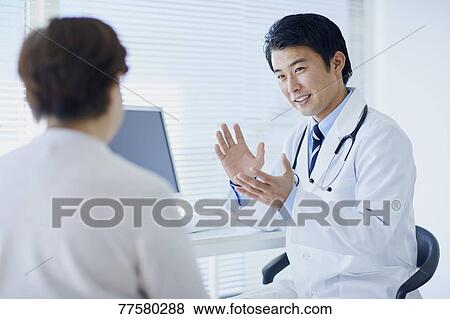 Stock Photo - Japanese doctor with a patient in his studio. Fotosearch