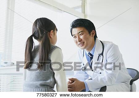 Stock Photo - Japanese doctor with a patient in his studio. Fotosearch