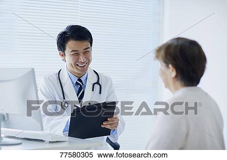 Stock Photography - Japanese doctor with a patient in his studio. Fotosearch