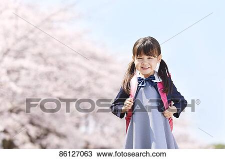Stock Image - Japanese elementary schoolgirl and cherry blossoms. Fotosearch