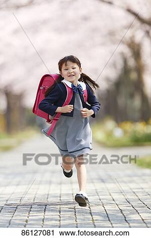 Stock Image - Japanese elementary schoolgirl and cherry blossoms. Fotosearch