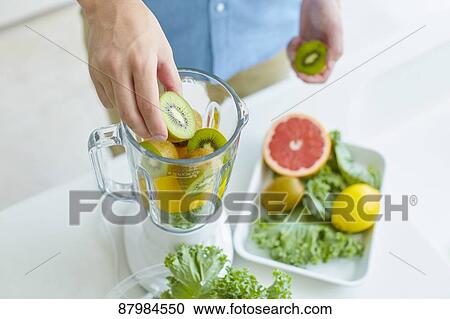 Stock Image - Japanese man making smoothie in the kitchen. Fotosearch