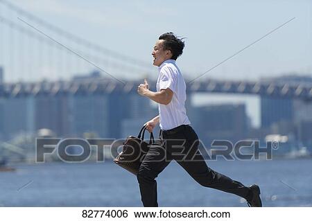 Stock Photograph - Japanese man running downtown Tokyo. Fotosearch